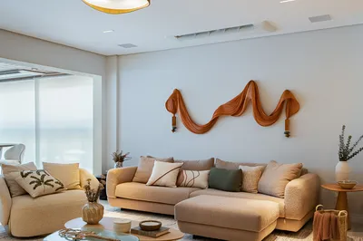 Sala de estar com sofá bege e escultura decorativa na parede — reforma de apartamento