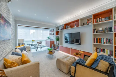 Sala de estar com parede de tijolos brancos e estante planejada — apartamento reformado Santos